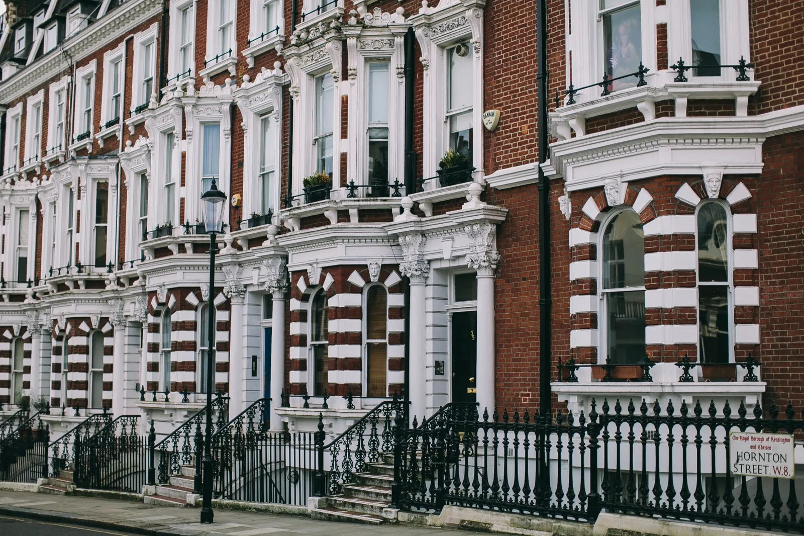 Row of Victorian brick terraced houses in London with bay windows and front railings